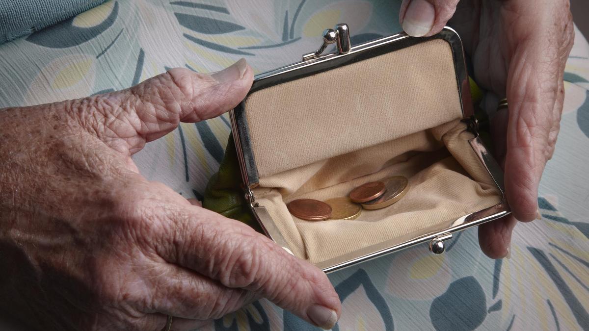 Senior woman holding open a purse on her lap